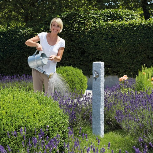 Ozdobny punkt poboru wody w ogrodzie. Imitacja jasnego granitu.